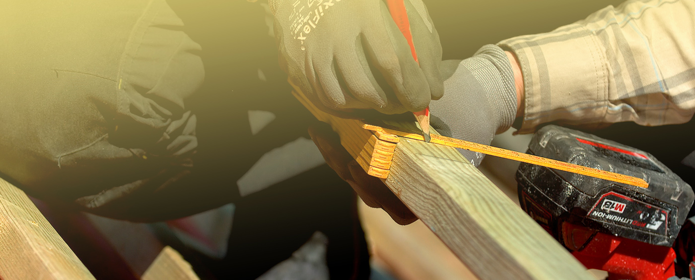 Close-up foto av håndverker som måler opp tømmer på tak.