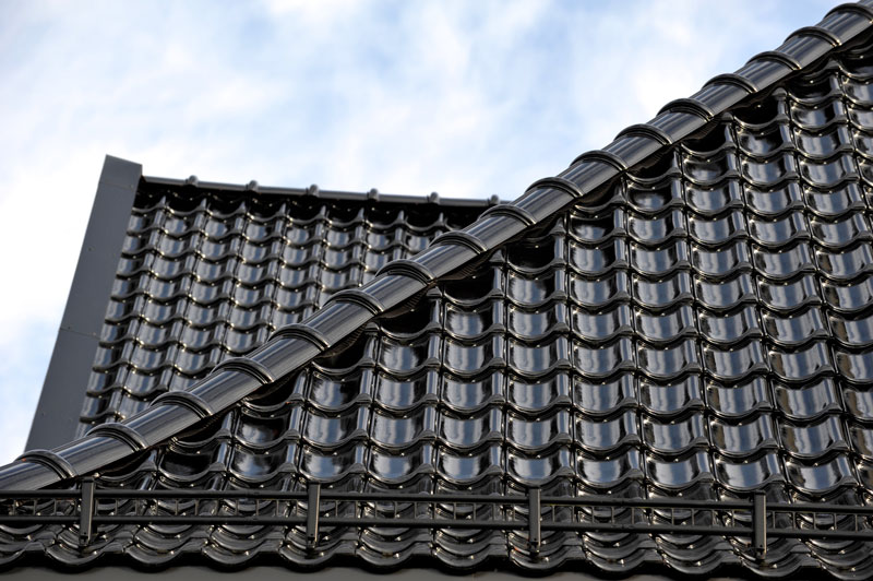 Foto av svart glasert takstein, sett fra siden.